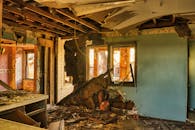 A view of a severely damaged room in an abandoned home, showcasing destruction and rubble.