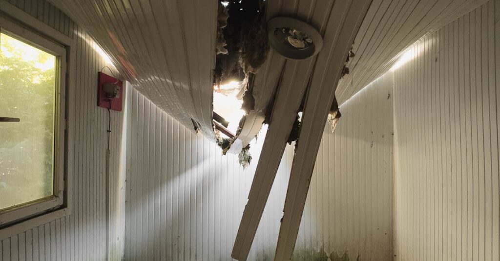Interior of a room with a collapsed ceiling showing damage and debris.